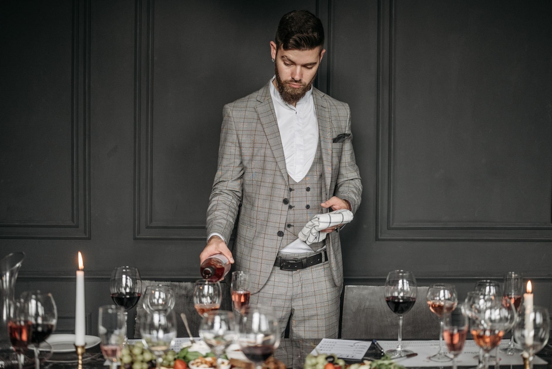 Sophisticated sommelier pours red wine at an elegant dinner setting, creating a chic atmosphere.
